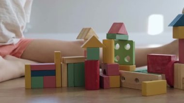 Çocukların elleri renkli küplerin inşaatını mahvediyor. Çocuklar oyuncak ev yapar. Kızgın çocuk. Mimarlık. Yeşil, kırmızı, sarı renk.