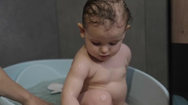 Матери руки моют игривая девочка в ванной. Уход за кожей. Уход за ребенком. — стоковое видео