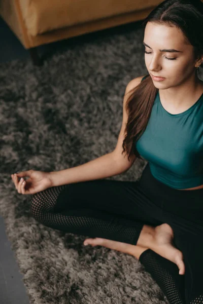 Närbild porträtt av sportig kvinna utövar och sitter i yoga lotus position på matta hemma. För livsstilsdesign. Hälsosam livsstil. Flicka — Stockfoto