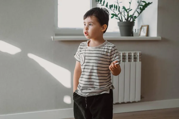 Ragazzo in piedi in casa con la mano in tasca e raccontando ai genitori com'era il primo giorno di scuola. Ritratto alla moda. Foto all'interno. — Foto Stock