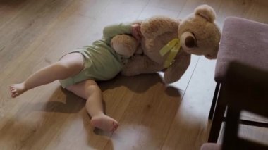 Küçük kız yere uzandı ve ailesinin doğum gününde ona verdiği oyuncak ayıyla oynadı. Bebek bakımı.