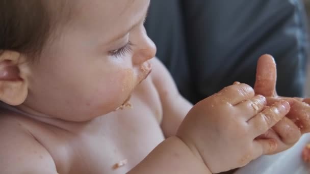 赤ちゃんの女の子は汚れた指を舐め、心のこもった朝食の後に顔。いい子だ。肖像画を閉じる. — ストック動画