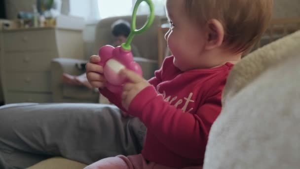 Ritratto ravvicinato di una bambina caucasica che gioca con il suo giocattolo sul divano e sorride. Un bambino sorridente e felice. Educazione dei bambini. — Video Stock