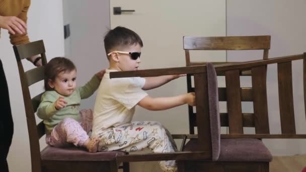 Πλευρική άποψη ενός έξυπνου αγοριού που παίζει με την αδερφή του σε έναν αυτοσχέδιο αγώνα αυτοκινήτων στο σπίτι. Σύγχρονος τρόπος ζωής. Φροντίδα μωρών. — Αρχείο Βίντεο