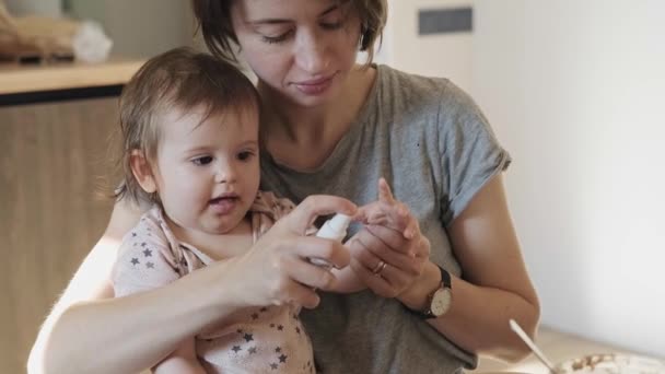 Az anya fertőtlenítőszerrel lefújta a babák kezét, és véletlenül szemen találta. Egészségügyi ellátás. Családi gondozás. Gyermekgondozás. — Stock videók