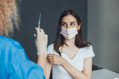 Doktorların elindeki enjeksiyondan korkan bir hastanın portresi. Coronavirus aşı kampanyası. Doktor Corona 'ya virüs aşısı yapıyor.