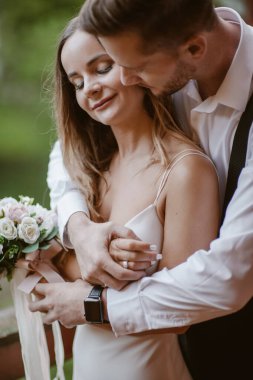Gelin ve damadın buket pozuyla yakın plan portresi. Damat düğün günlerinde yanaktan sarılıp öpüyor..
