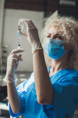 Maske takan ve hasta için aşı hazırlayan eldiven takan kadın doktor. Corona virüsü aşılama. Yakından bir portre. Tıbbi bakım.