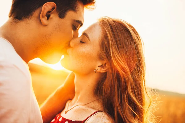 Мальчик и девочка целуются на первом свидании в свете осеннего солнца. Портрет на светлом фоне. Портрет крупного плана. — стоковое фото