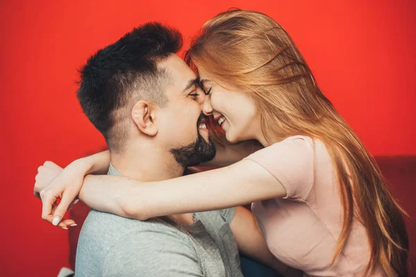 Ευτυχισμένο νεαρό καυκάσιο ζευγάρι ερωτευμένο να φιλιέται όταν περνάει το βράδυ απομονωμένο σε κόκκινο φόντο. Διακοπές, γενέθλια. Ημέρα του Αγίου Βαλεντίνου. — Φωτογραφία Αρχείου