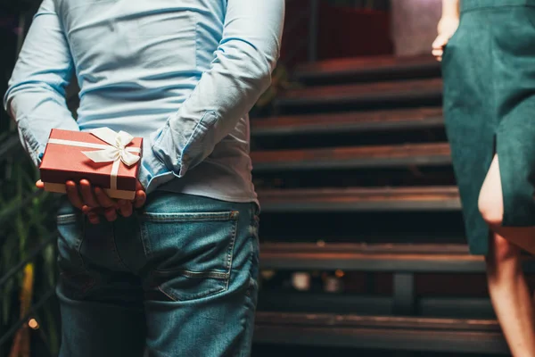 Mannen gömmer presentförpackning i en bar och väntar på att flickvännen ska gå ner. Presentförpackning. Familjehelg. Familjedag. — Stockfoto