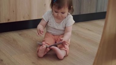 Bebek elinde kitapçıkla yerde oturuyor, sırtüstü düşüp karnının üstüne yatarken oynuyor. Enerjik bir çocuk. Çocuk gelişimi. Bebek gelişimi