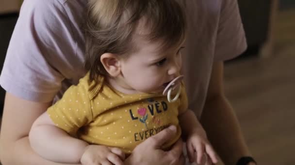 Madri mani cercando di tenere la sua inquieta figlia tra le braccia. Si tiene per mano. Cura del bambino. — Video Stock