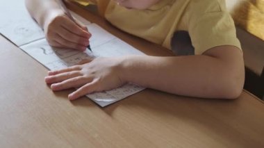 Çocuk masasında oturuyor ve Romence mektup yazmayı öğreniyor. Eğitim konsepti yazmak. Çocuk gelişimi. Okul sınıfı..