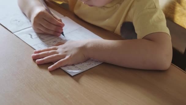 The boy is sitting at his desk and learning to write letters in Romanian. Writing education concept. Child development. School class. — Stock Video