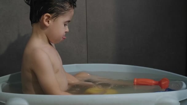 Προβολή προφίλ ενός αγοριού που κάνει μπάνιο σε ένα μπάνιο παίζοντας με ένα κίτρινο καουτσούκ πάπια παιχνίδια. Υγεία. — Αρχείο Βίντεο