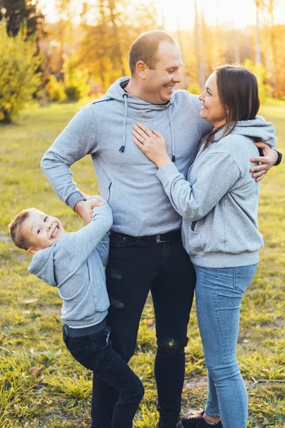Portrét šťastné rodiny tří členů, procházejí se spolu v parku a komunikují. Držím se za ruku. Letní prázdniny. Rodinná péče. — Stock fotografie
