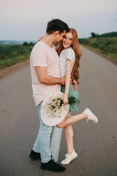 Casal caucasiano amoroso enquanto abraça no meio da estrada rural. Viagem de casamento. — Fotografia de Stock