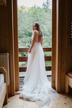 Yazın güzel orman manzaralı, özel kulübenin ahşap balkonunda duran gelin portresi. Güzel kız. Yaz stili. Arka plan.