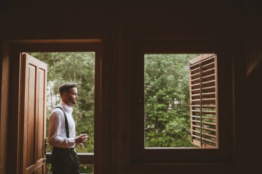 Tahta balkonda durup manzaranın keyfini çıkarırken gülümseyen profil uzmanı. Wdding Günü.