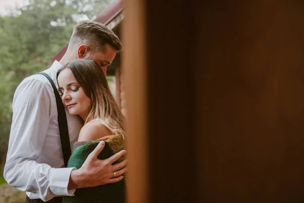 Primer plano retrato recién casados abrazando de pie en la casa de madera por la noche. Día de la boda. — Foto de Stock