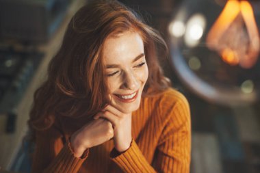 Başarılı bir şekilde gülümseyen ve ellerini çenesinin altında tutarak başını çeviren kadın. Yakından bir portre. Güzellik, moda. Moda modeli.