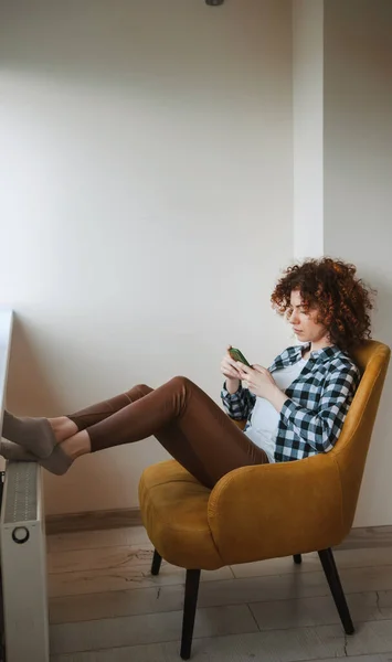 Lockig kvinna sitter på fåtölj och pratar online med sin mobiltelefon. Använda telefon. Affärskvinnans porträtt. Mobilkommunikation. — Stockfoto
