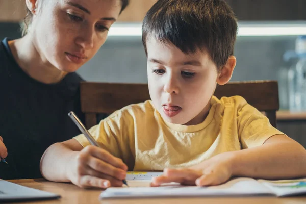 Madre caucásica ayudando a un niño con la tarea en casa. Cuarentena, pandemia. —  Fotos de Stock