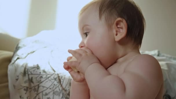Очаровательная малышка ест кусочки банана, сидящего на кровати. Семейная концепция. Портрет крупного плана. Уход за ребенком. — стоковое видео