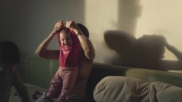 Mamá pasa la tarde jugando con sus dos hijos sentados en el sofá juntos, divirtiéndose. Concepto de alegría. Concepto familiar. Concepto de paternidad. Cuidado del bebé. — Vídeos de Stock