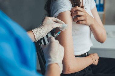 Beyaz eldivenli doktor klinikteki bir kadının koluna COVID 19 koronavirüs aşısı yapıyor. Coronavirus önleme. Kadın aşı oluyor.