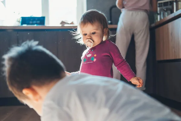 Ritratto di due bambini gioiosi, fratello e sorellina che giocano insieme sul pavimento della cucina di casa. Infanzia, concetto di sicurezza dei bambini. Famiglia impegnata — Foto Stock