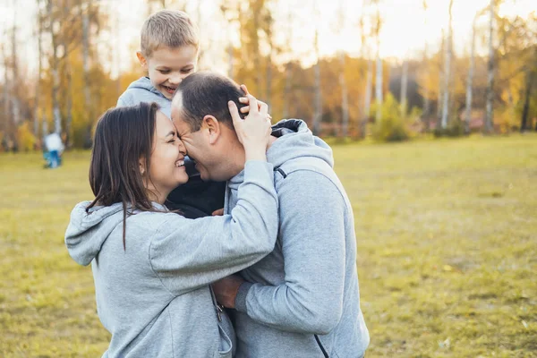 Šťastná rodina: otec, matka a malý syn se baví venku, hrají si, smějí se a objímají se v podzimním parku. Rodinný den. Slunečný den. Šťastná rodina. — Stock fotografie