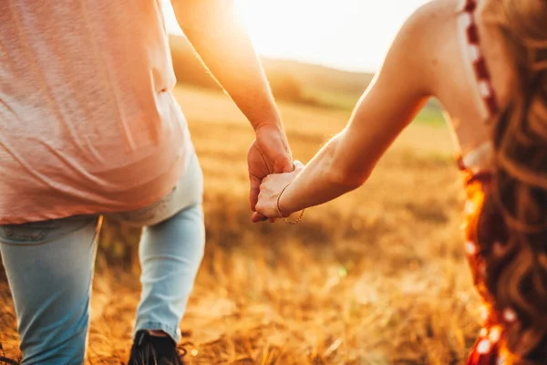 두 사람 이 손을 잡고 아름다운 일몰을 맞이하는 황금빛 밀밭을 걷고 있다. 여름 방학이야. 가을 풍경. 가족 개념. 자연 경관. — 스톡 사진