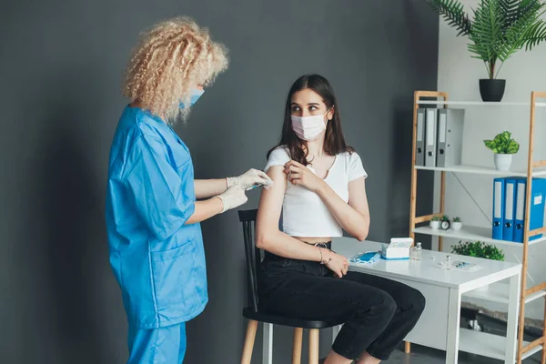 Kıvırcık saçlı tıbbi personel hastanedeki hasta koluna aşı yapıyor. Coronavirus pandemik koruma konsepti. Pandemik önleme. Sağlık hizmetleri