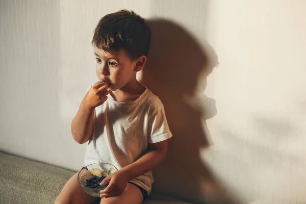 Las manos del niño tocan y toman arándanos frescos crudos en el interior. Hermoso chico comer arándanos, gran diseño para cualquier propósito. —  Fotos de Stock