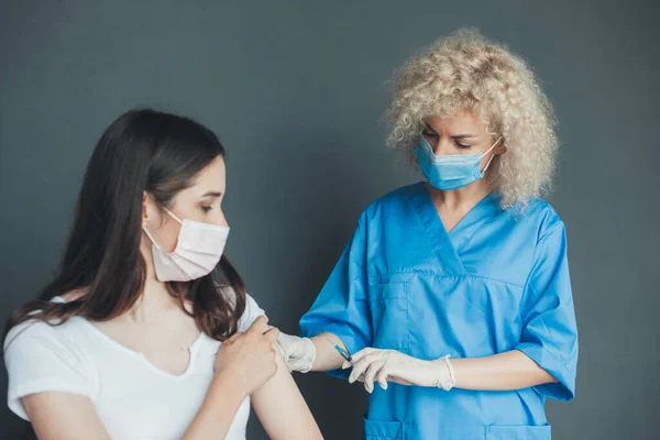 Personil medis memvaksinasi seorang wanita muda Kaukasia. Dokter memberikan suntikan virus korona kepada pasien. Konsep layanan kesehatan. Pandemi Coronavirus — Stok Foto