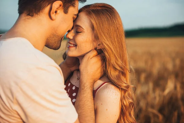 Un couple touchant les fronts étant romantique et embrassant tout en posant sous la lumière du soleil avec un fond flou. Amour et relations à l'extérieur. — Photo