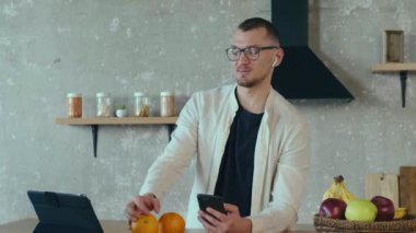 Freelancer akıllı telefondan konuşuyor ve mutfakta tablet kullanıyor. Mobil iletişim. Video konferansı. Konuşan insanlar. Konferans görüşmesi. Çevrimiçi video. Uzak