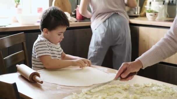 Boy at the table in the kitchen helping grandmother cooking from dough. Family time in the cozy kitchen. Autumn activity at home. — Stock Video