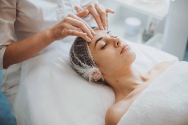 Beyaz kadın spa salonunda köpük yüz masajı yaptırıyor. Yüz bakımı. Vücut bakımı. Güzellik tedavisi. Kozmetik güzellik prosedürü. Tıbbi tedavi