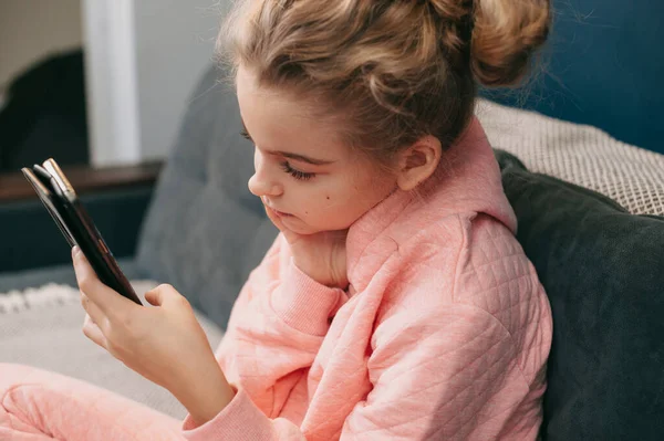 Retrato de una chica escribiendo un mensaje corto en el teléfono móvil sentado en el sofá, en el interior. Hermoso retrato. Usar teléfono. — Foto de Stock