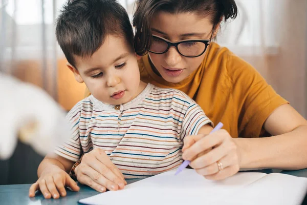 Madre enseñando a su hijo a escribir su nombre. Trabajo y educación desde el hogar para prevenir coronavisrus COVID-19, concepto de autocuarentena —  Fotos de Stock