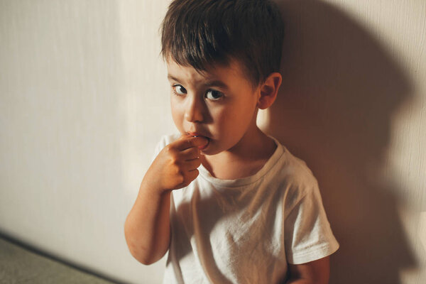 Boy looking suspiciously at the camera as he put a blueberry in his mouth. Fresh healthy food.