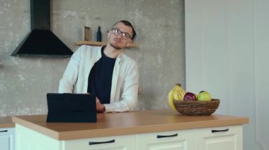 İş adamı, mutfakta elinde portakal tutarken arkadaşlarıyla konuşan bir tablet giyer. Mobil iletişim. El ele tutuşarak