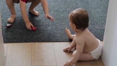 Küçük çocuklar, çocuklar, kız ve erkek çocuklar yerde oyuncak araba oynuyorlar. Bebek gelişimi. Gülümseyen mutlu çocuk. Bebek bakımı. Aile bakımı.