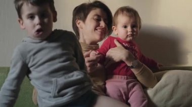 Üç kişilik aile evlerinin oturma odasındaki kanepede oturup eğleniyorlar. Bebek bakımı. Aile bakımı.