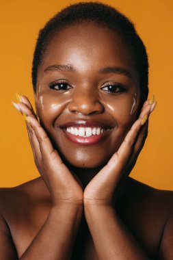 Hidrojel bantlar süren aro kadının portresi. Gülümseyen, nazikçe dokunan, sarı arkaplanda izole edilmiş. Cilt bakımı. Yüz bakımı. Sağlıklı