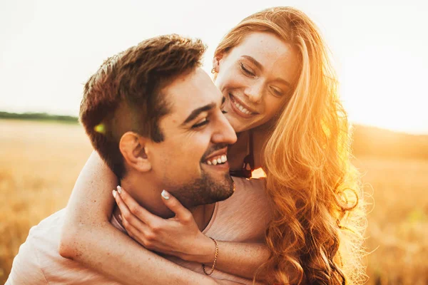 Portrait of a red-haired girl happy with time spent with her boyfriend outdoors, hugging him from behind with love. Sunny day. Family day. — Stockfoto