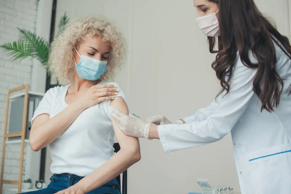 Doctorul vaccinează o femeie în clinică. Conceptul de sănătate. Conceptul de vaccinare împotriva gripei pentru imunizarea coronavirusului. — Fotografie, imagine de stoc